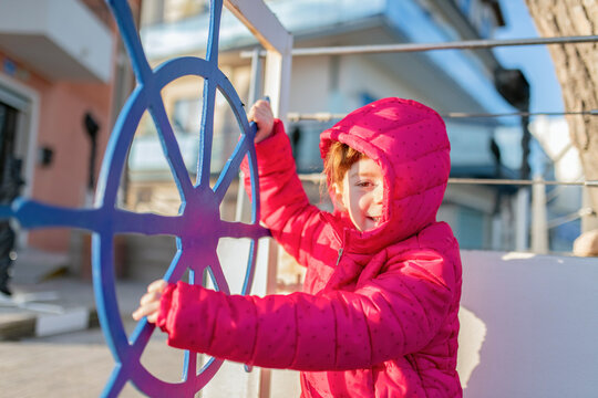 Bambina sorridente che gira un timone della nave