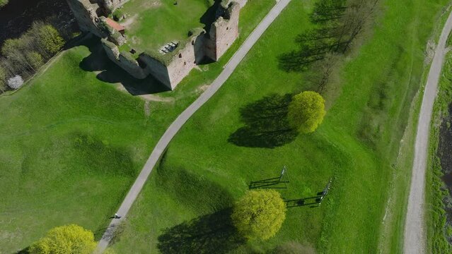 Aerial establishing view of Bauska Medieval Castle and ruins, Musa and Memele rivers next to the castle, sunny spring day, drone shot moving backward, camera tilt up
