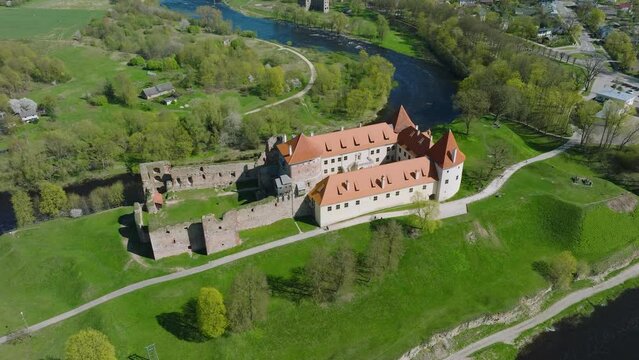 Aerial establishing view of Bauska Medieval Castle and ruins, Musa and Memele rivers next to the castle, sunny spring day, orbiting drone shot