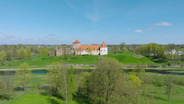 Aerial establishing view of Bauska Medieval Castle and ruins, Musa and Memele rivers next to the castle, sunny spring day, wide drone shot moving forward
