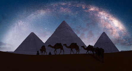 Camel caravan in front of the Great pyramid of Giza complex - The Milky Way rises over the Pyramids...