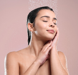 Woman, relax and shower with water for hygiene, stress relief or wash on a pink studio background. Face of calm female person or young model with natural liquid for skincare, hydration or cleanliness