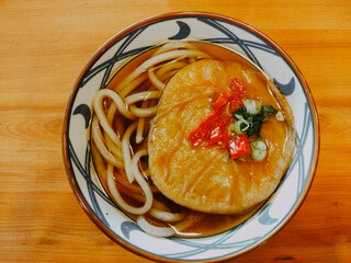 close up of maruten udon. it is noodle with savory fried fish cake. it is served  on the wooden table