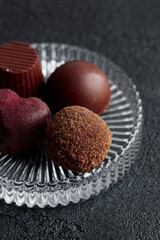 Delicious gourmet chocolate handmade truffles from confectionery, homemade dark chocolate candies on plate and black background