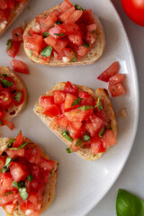 Homemade Bruschetta with Basil and Tomatoes on a Plate, top view.