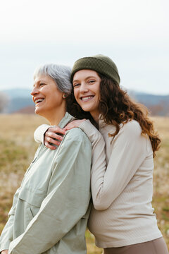 Happy mother and pregnant daughter hugging in nature