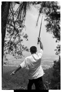 Samurai dancing sword under pine trees