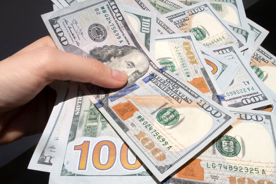 Holding a pile of hundred dollar bills closeup