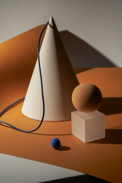 White gypsum cone, cube, and spheres connected by a blue wire.