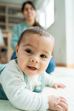 Joyful baby with mother in background