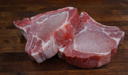 Two pork entrecotes lie on a wooden cutting board. Pork .