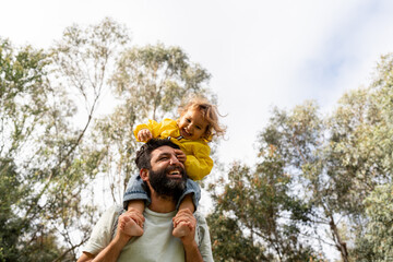 Dad holding his daughter on his shoulder and laughing.