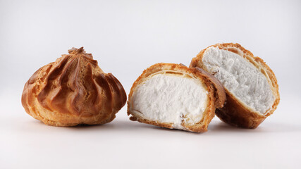 Cut in half and whole porophytole with white cream isolated on a white background. Eclair with cream.