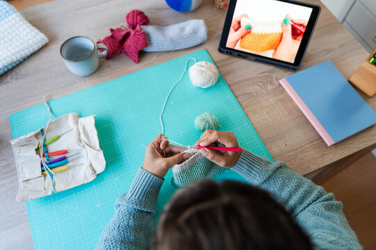 Overhead view of person knitting following online tutorial