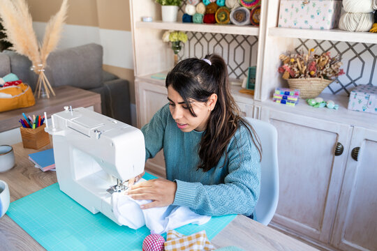 Focused woman using a sewing machine for crafting 