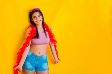 brunette latina woman, with a big smile and wearing carnival clothes, posing on a yellow background.