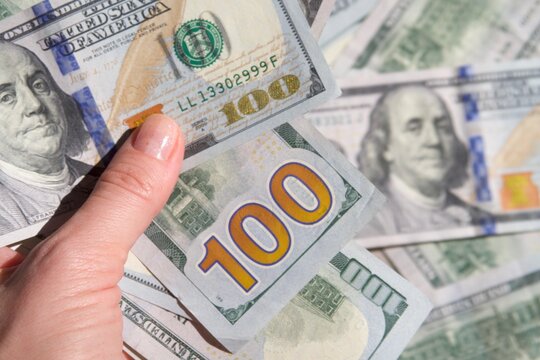 Holding a pile of hundred dollar bills closeup