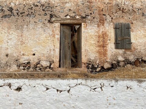 Abandoned ruined building with open wooden door.