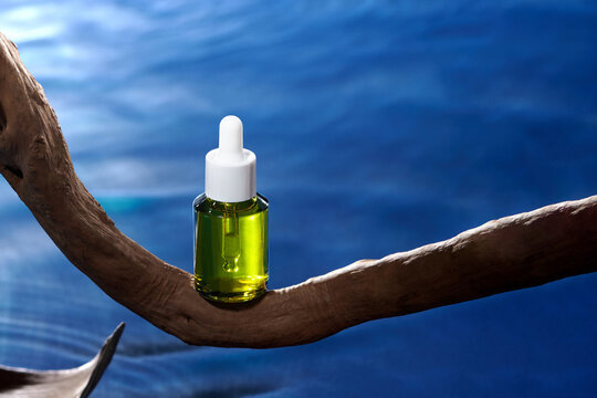 The collagen hydrating serum stands on driftwood over blue water