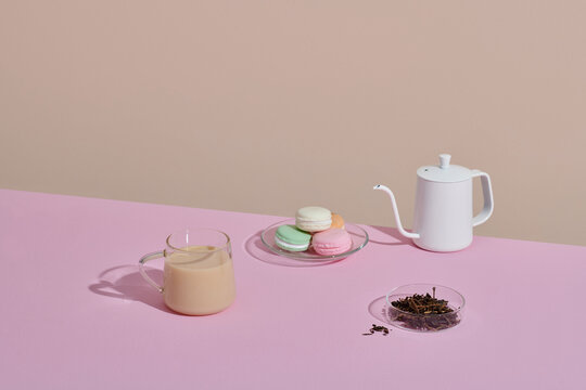 Cup of tea with teapot and fresh milk cup on pink table.