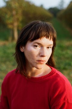 Serene Young Woman in Red Sweater Outdoors at Dusk