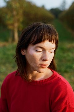 Serene Young Woman in Red Sweater Outdoors at Dusk