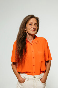 Cheerful elderly woman in orange shirt looking at camera