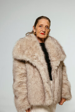 Serious senior woman in fur coat at studio