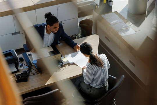 Smiling manager discussing with colleague at desk