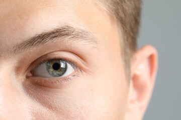 Perfect vision. Man with beautiful eyes on grey background, closeup