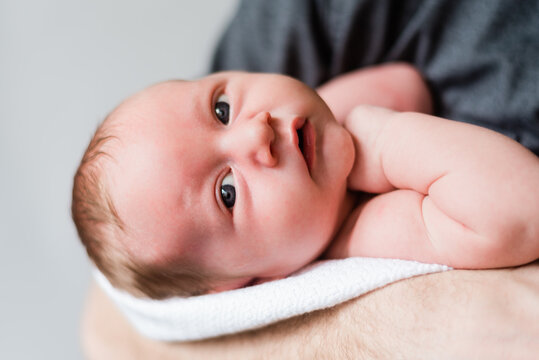 Alert newborn with expressive eyes lies cozily wrapped