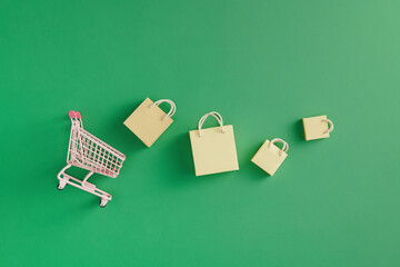 Paper shopping bags in a shopping cart on green
