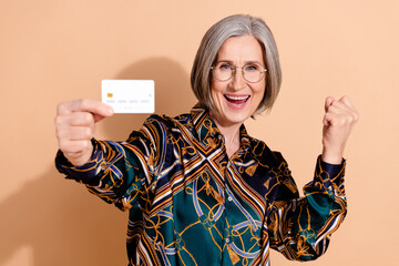 Portrait of ecstatic senior woman wear print blouse in glasses demonstrate credit card scream yeah...