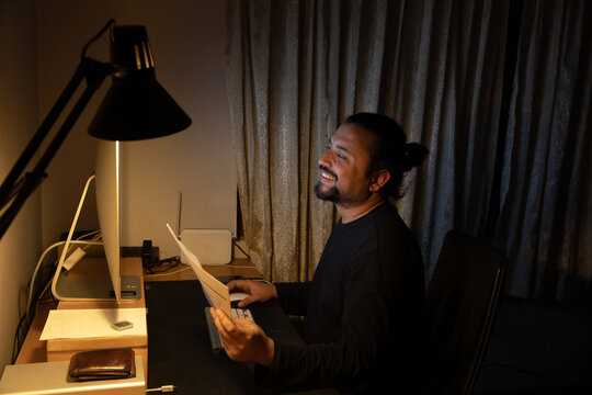 Man smiles at the screen in front of a computer.