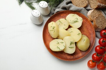 Plate with young boiled potatoes, dill and products on white table, flat lay. Space for text
