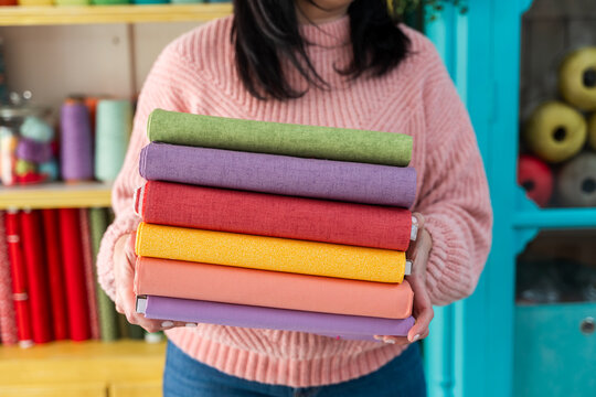 Woman carrying stack of colorful folded fabrics