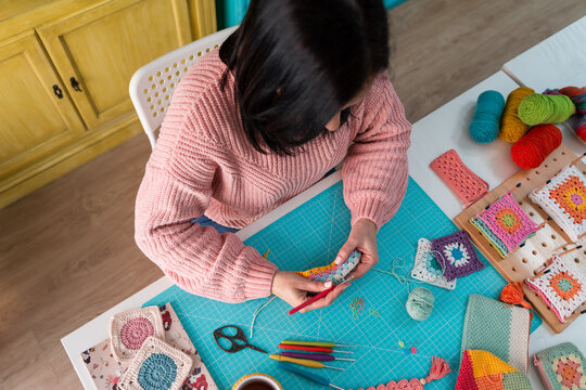 Woman crafting colorful crochet patterns on table