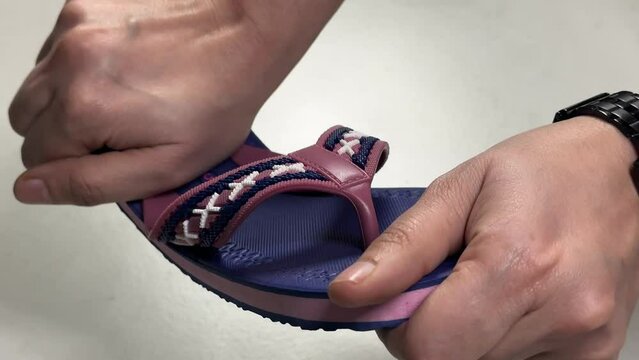 Close-up view 4k stock video footage of new pair of soft and flexible eva slippers in hands of woman