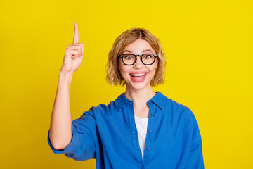 Photo of nice young girl point finger wear blue shirt isolated on yellow color background