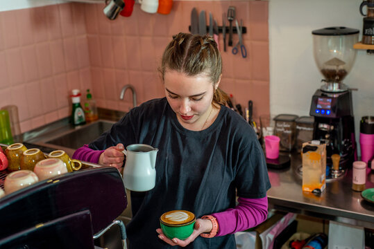 Female barista makes coffee near the coffee machine. 