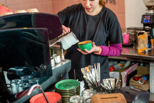 Female barista makes coffee near the coffee machine. 