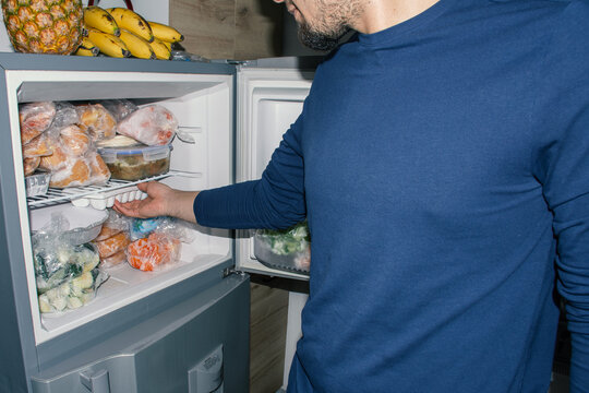 Man Taking Ice Cubes from Fridge with Frozen Ingredients