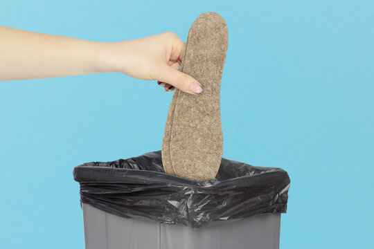 throw felt insoles for shoes in the trash, outstretched hand with felt insoles  in front of trash can