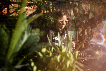Woman DJ wearing colorful glasses mixing surrounded by plants at party