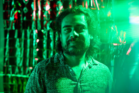 Man with colorful shirt lit by green light looking at the camera - Powered by Adobe