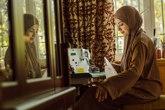 A young Muslim woman putting thread in a sewing machine