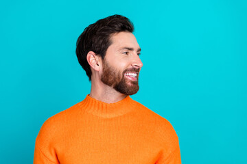 Photo of cheerful handsome man wear orange trendy pullover look empty space isolated on cyan color...