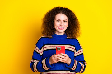 Portrait of lovely positive woman with wavy hair wear knit sweater holding smartphone toothy...