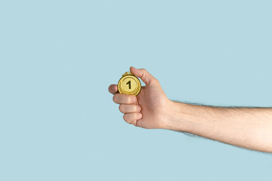 Person holding first prize gold medal. Success, competition, winner.