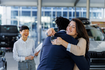 Couple hugging after getting keys to new car